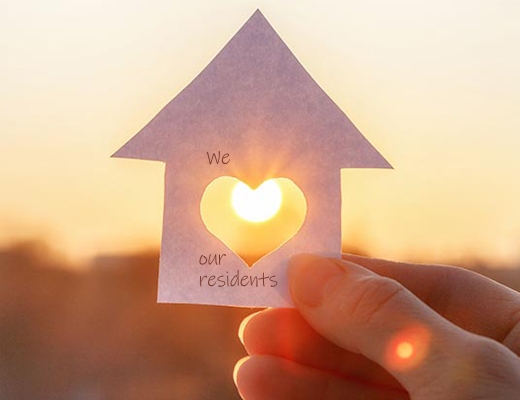 Paper house in front of sunrise that says "We Love Our Residents"