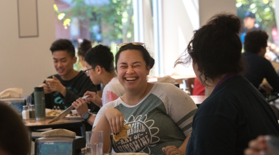 Student laughing while eating at dining center